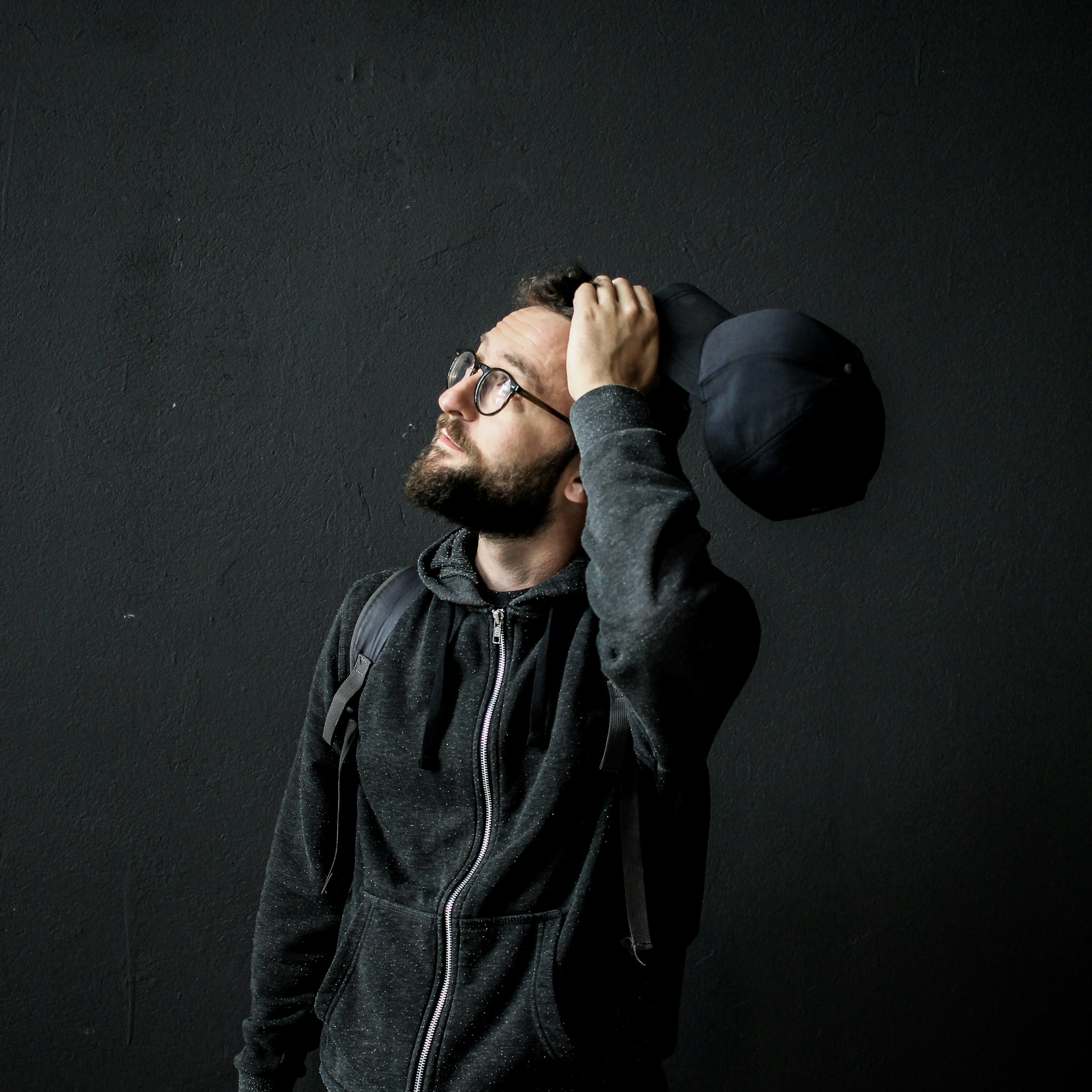 A professional portrait of a designer with short dark hair and a thoughtful expression against a soft, neutral backdrop.